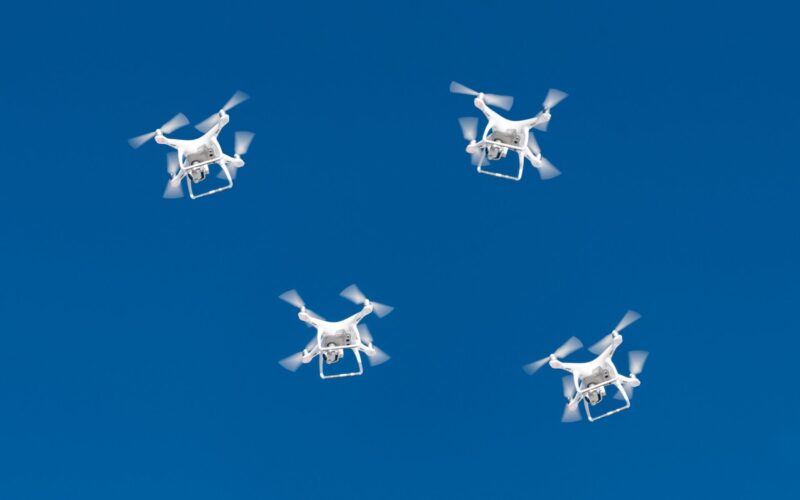 A drone swarm flying in a blue sky