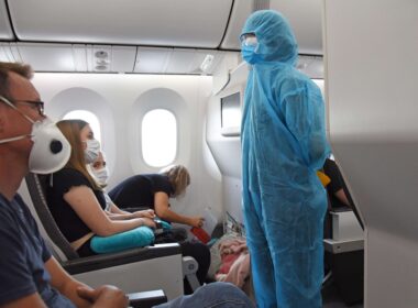 air_stewardess_crew_member_prepares_to_conduct_the_safety_briefing_for_passengers_on_board_a_charter_flight_wearing_full_ppe_hazmat_suit_during_the_corona_pandemic-5.jpg