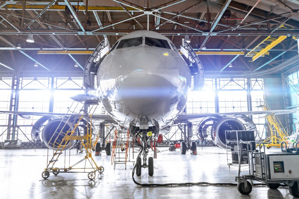 Aviation hangar with passenger aircraft jet for maintenance. Bright lights lighting, glare.